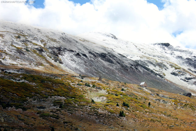 Snow-dusted mountainside with a small cabin in the foreground.