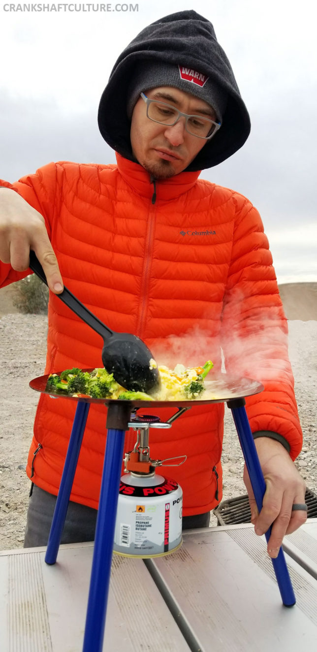 Andy using plastic utensils to cook on the Tembo Tusk Adventure Skottle. 