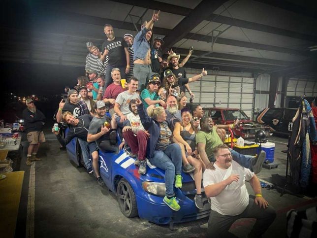 Zac Caldwell (front) with a host of other people piled atop his 2006 Dodge Caravan race car. 