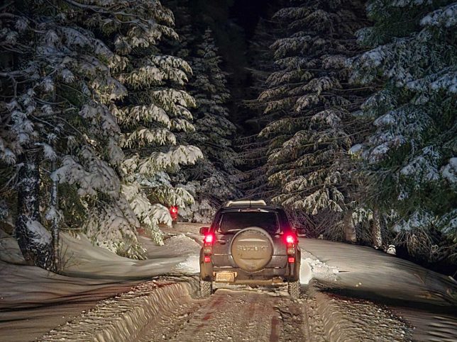 A Suzuki Vitara on a dark, snowy trail.