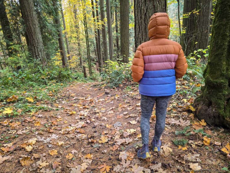 woman wearing Cotopaxi Fuego Max down jacket in woods back side hood up