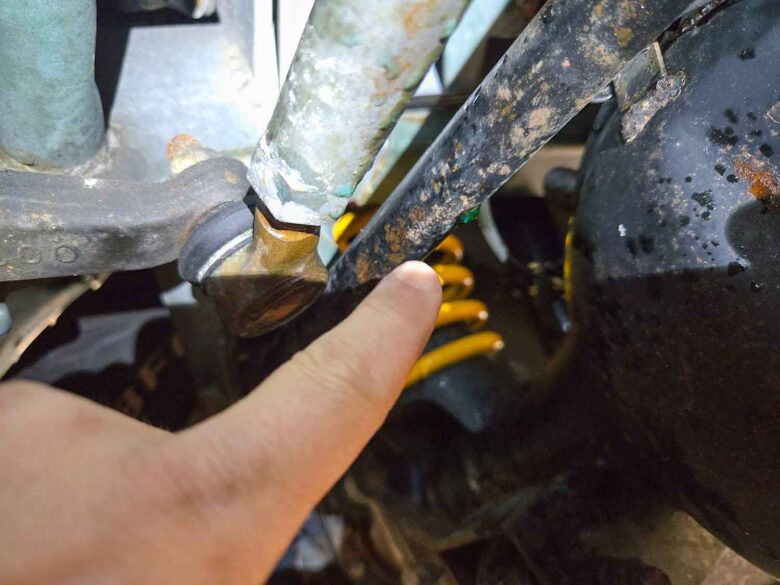 Coolant drips on a 1998 Suzuki Jimny Wide's suspension components.
