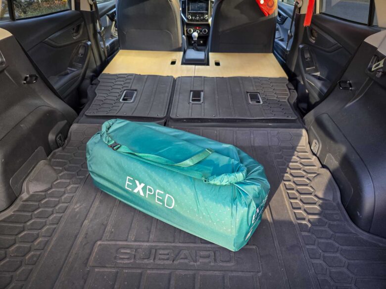 EXPED MegaMat Duo in medium size's travel bag, Sleep Rides sleeping platform set up with Subaru Crosstrek seats folded down.