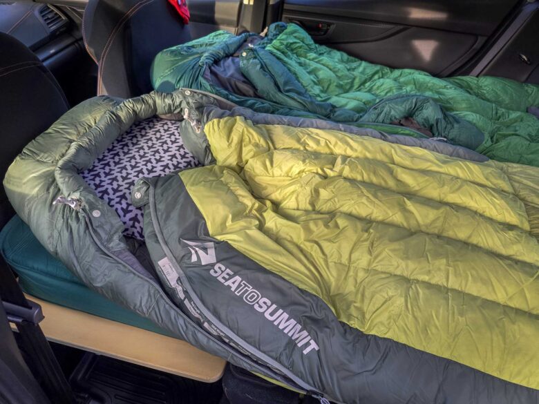 Women's specific and Unisex Sea to Summit Ascent Down Sleeping Bags laying on Sleep Rides sleeping platform in car