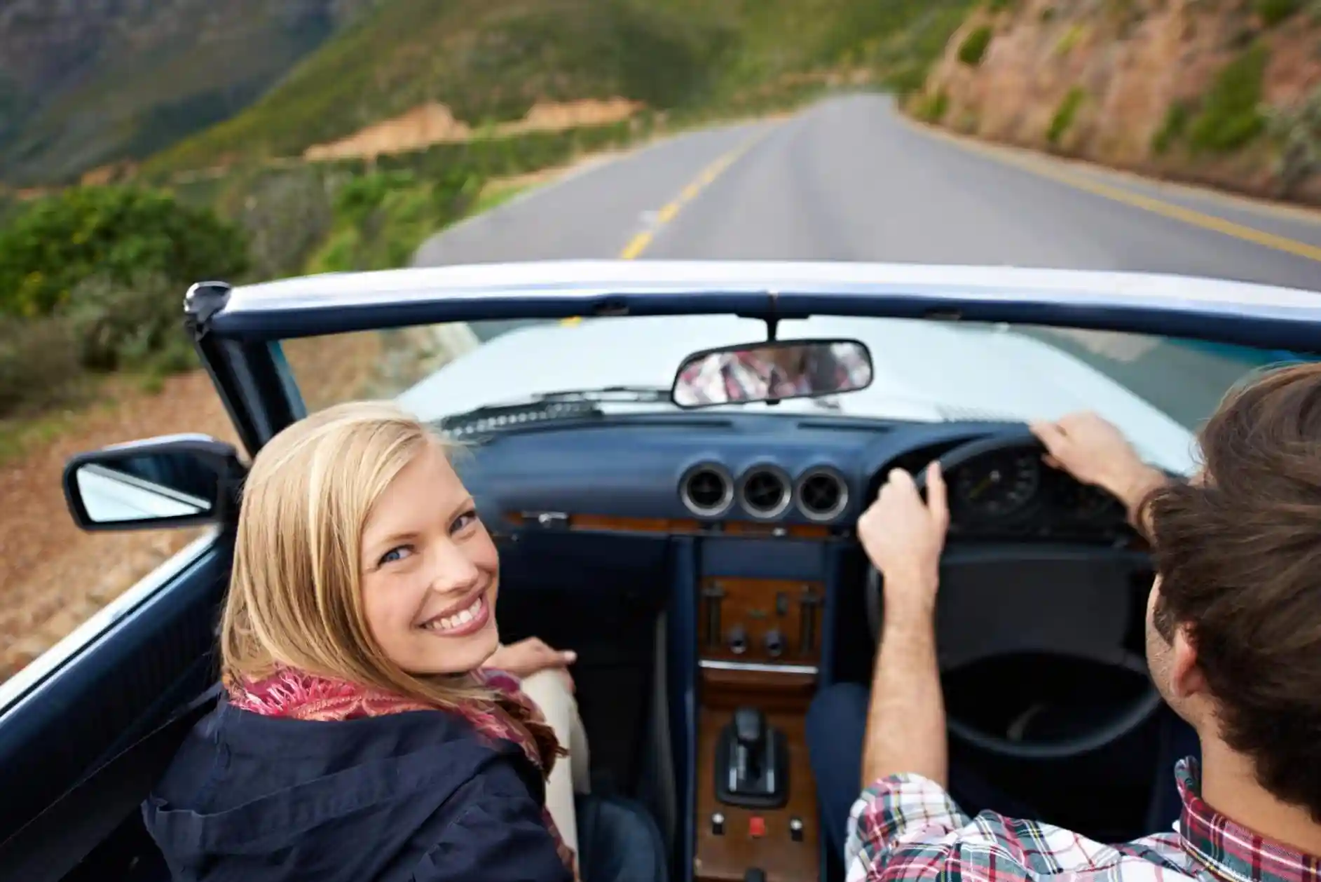 Woman and man in a convertible car driving