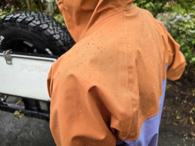 Cotopaxi Impermeo 3L Hooded Shell Jacket and water beading on shoulders